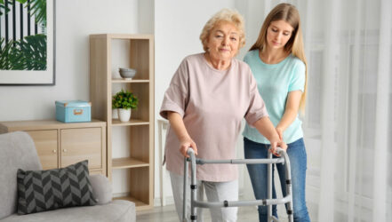 Young woman and her elderly grandmother with walking frame at ho